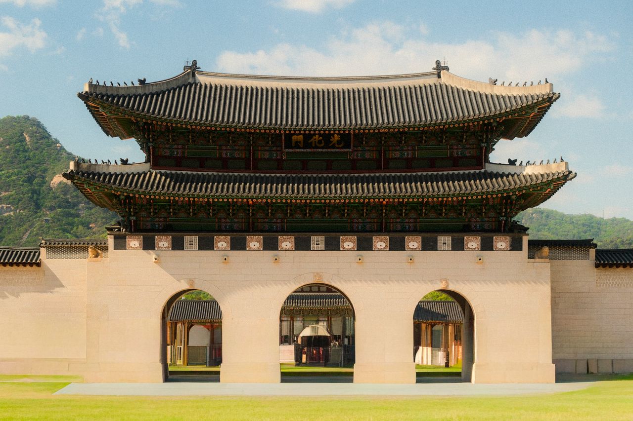 Gwanghwamun Gate, the main entrance of Gyeongbokgung Palace, under a clear daytime sky.